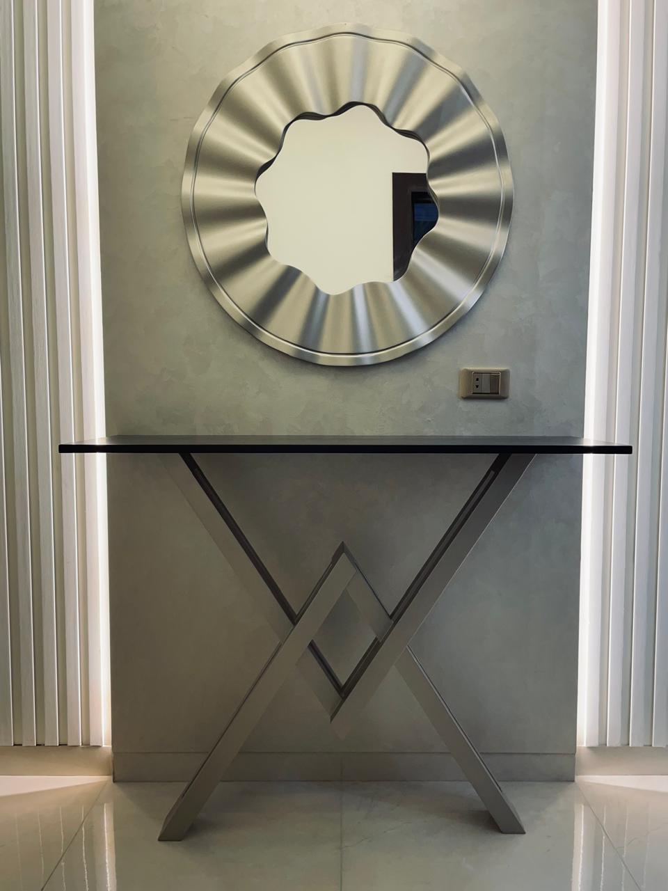 Modern wall mirror with decorative frame on a light gray wall.