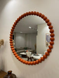 Round mirror with a wooden bead frame in a living room setting