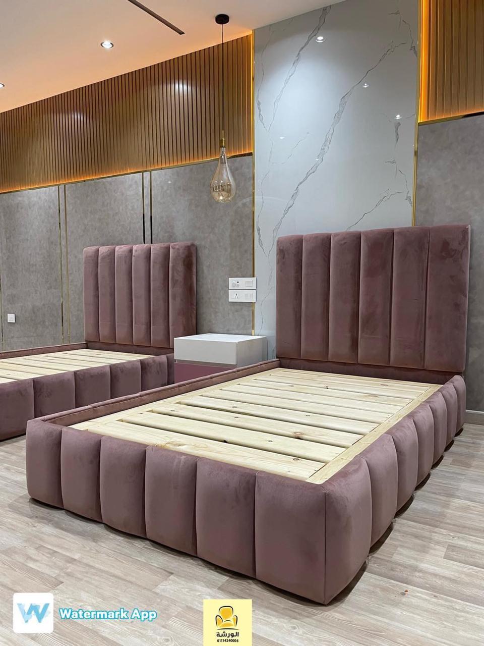 Purple upholstered bed frames in a modern bedroom setting with gray walls and wooden flooring.