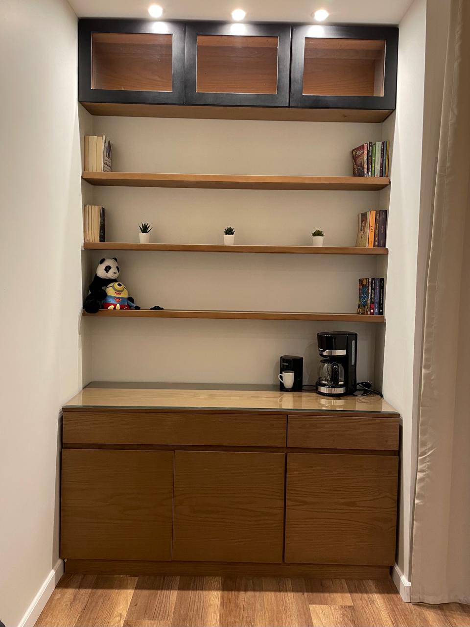Wooden shelves with books and decor items against a beige wall.