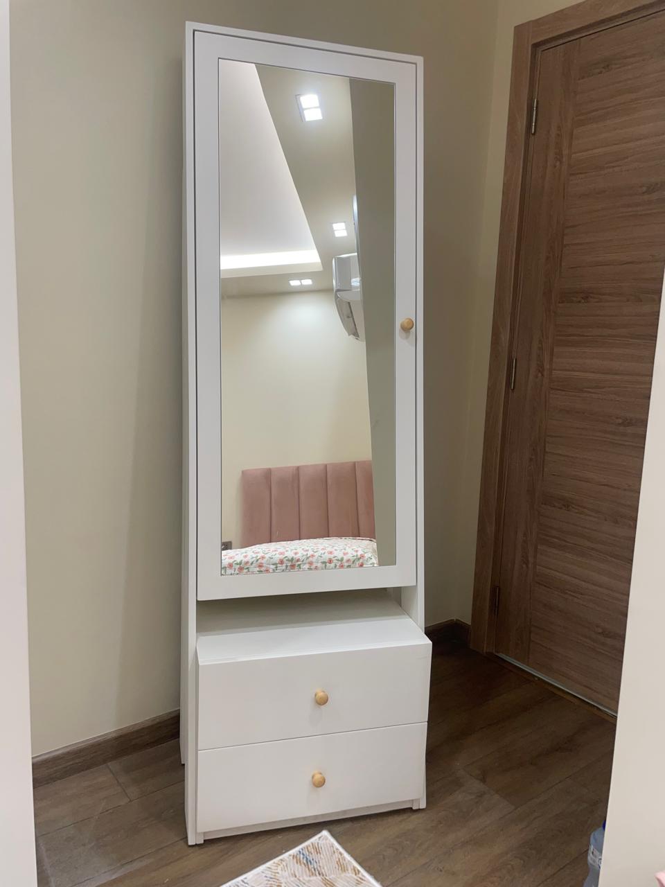 White cabinet with a mirror on a wooden floor.
