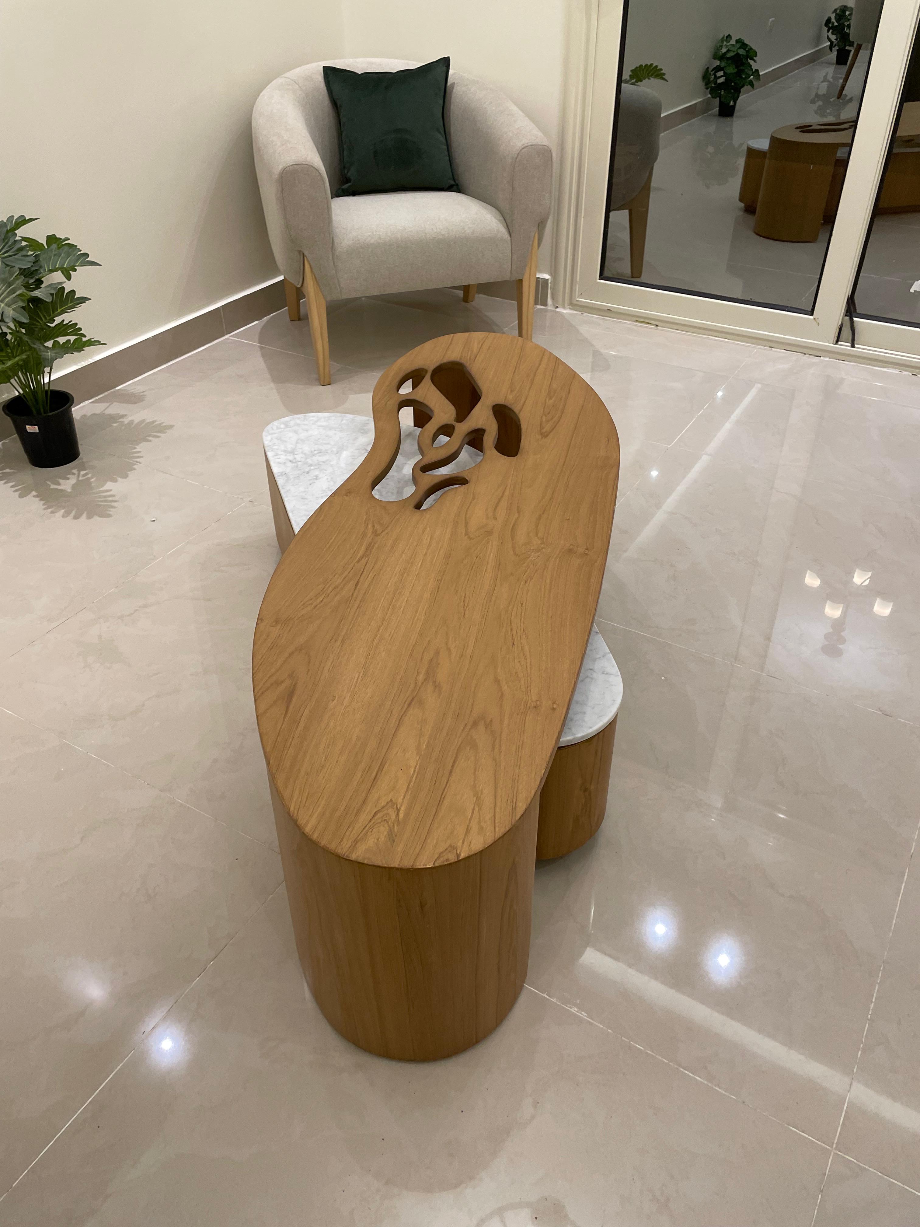 Wooden side table with decorative cutout design on a tiled floor.