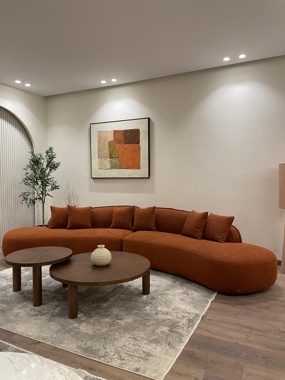 Modern living room with a brown sectional sofa, wooden coffee table, and abstract art on the wall.