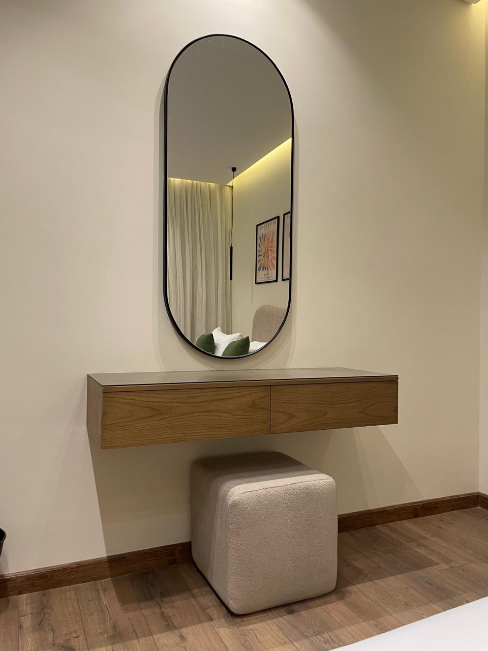 Dresser with mirror and stool against a wall