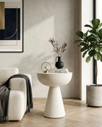 Modern living room with a white side table, armchair, and plant.