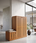 Wooden cabinet with a small cushioned stool in a modern interior setting.